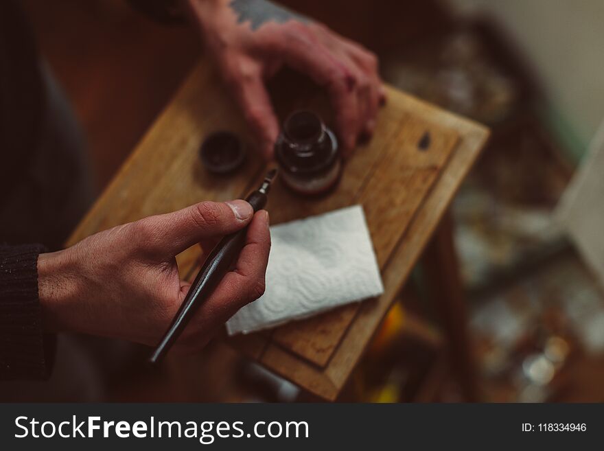 Hands of male artist, pen and ink for drawing on wooden table. Hands of male artist, pen and ink for drawing on wooden table