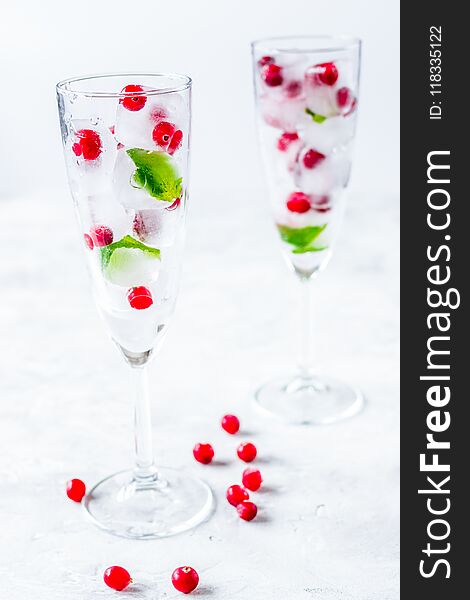 Ice cubes with fresh berries and mint in glasses for summer drink on white table background. Ice cubes with fresh berries and mint in glasses for summer drink on white table background