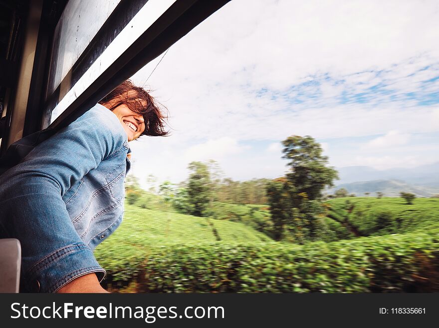 Happy woman looks out from train window during traveling on most picturesque train road in Sri Lanka