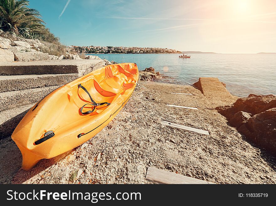 Bright orange kayak is on the stone sea pier