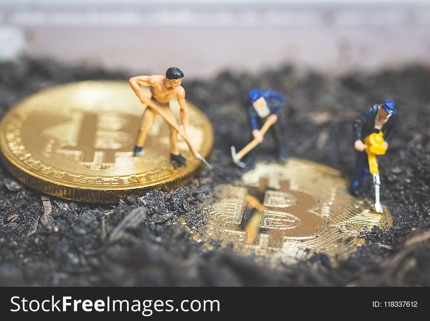 Miniature people : Worker team digging ground to uncover big shiny bitcoin