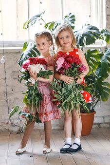Two Cute Little Girls With Peonies. Two Beautiful Friends Having Fun, Hugging And Smiling Stock Image