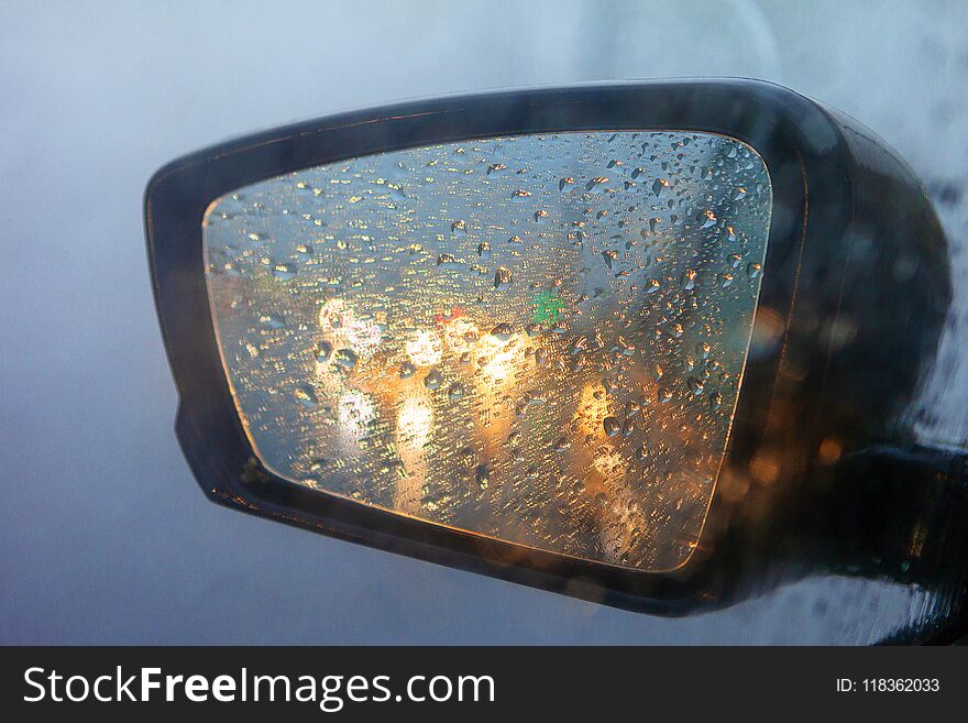 Rearview Mirror With Drops Of Water From The Rain And A Car With Headlights. Selective Focus, Shallow DOF