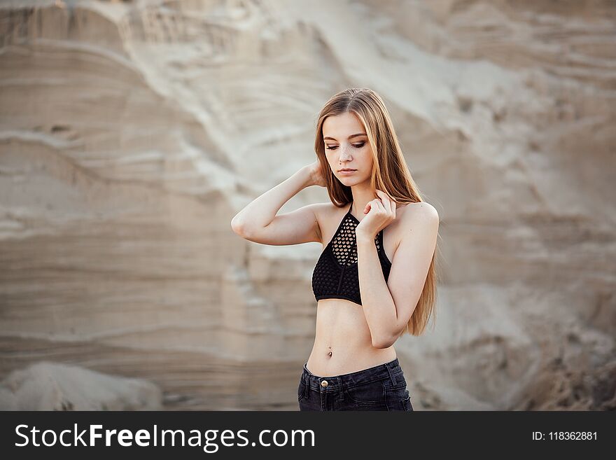 Portrait of a beautiful girl with long hair on the sands in the nature at sunset