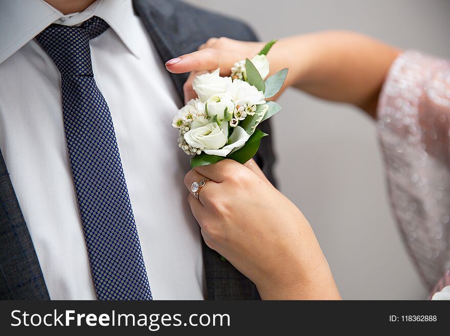 Bride fastens groom boutonniere to buttonhole