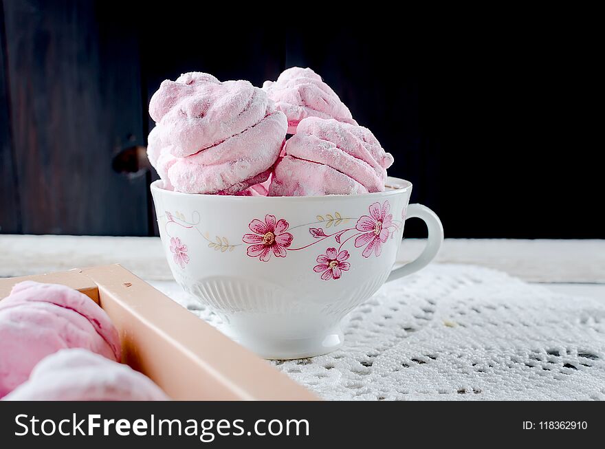 Homemade currant pink marshmallows - zephyr in cup on a white wooden background. Selective focus.