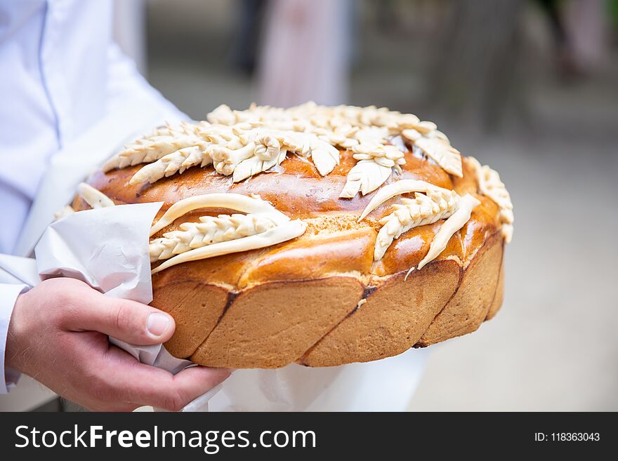 Man walking and holding traditional ukrainian wedding cake with spikelets. delicious loaf. wedding traditions