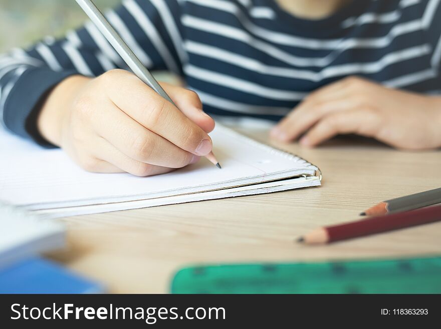 Kid holding pencil and writing in notebook. Close up. Kid holding pencil and writing in notebook. Close up.