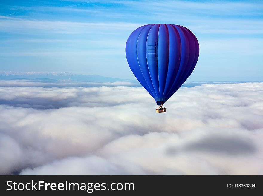 A lonely blue hot air balloon floats above the clouds. Concept leader, success, loneliness, victory