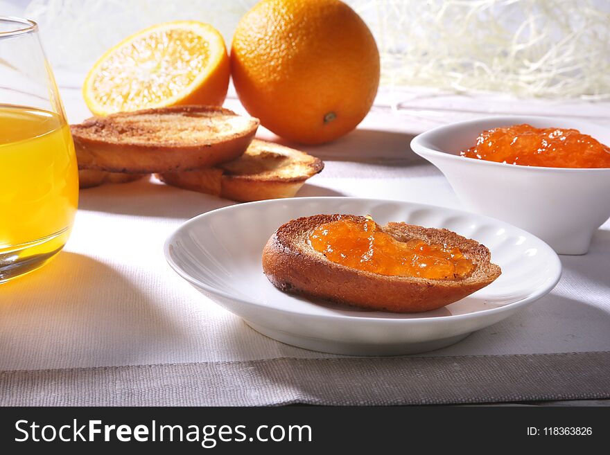 Morning Breakfast set with orange jam on bread toast and juice in glass.