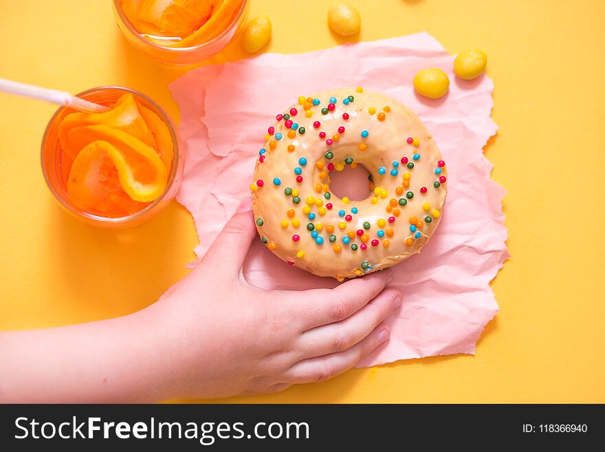 Donut on yellow background. Top view. Child's hand takes sweet pastry. Donut on yellow background. Top view. Child's hand takes sweet pastry