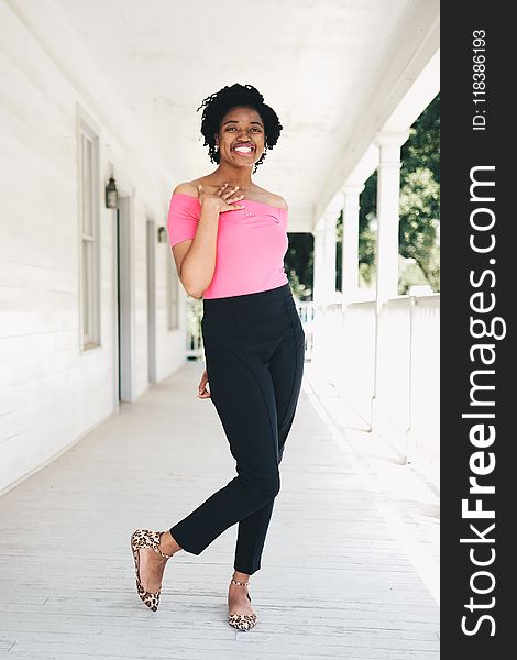 Woman Wearing Pink Off-shoulder Shirt and Black Pants While Standing Near Wall