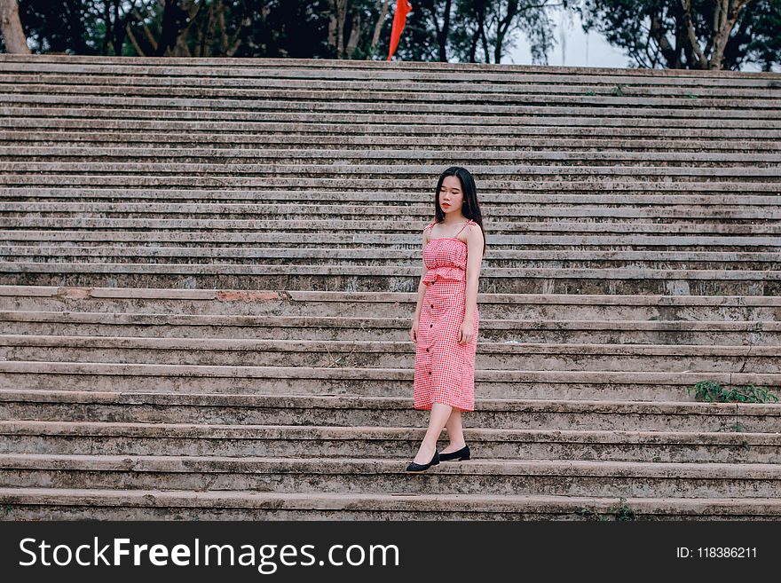 Woman Wearing Pink Spaghetti-strap Dress Standing on Grey Concrete Stairs