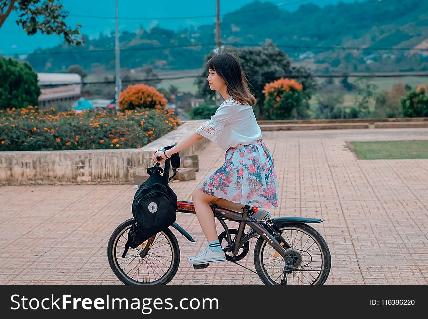 Woman Riding Bicycle Overlooking Orange Flowers and Hills