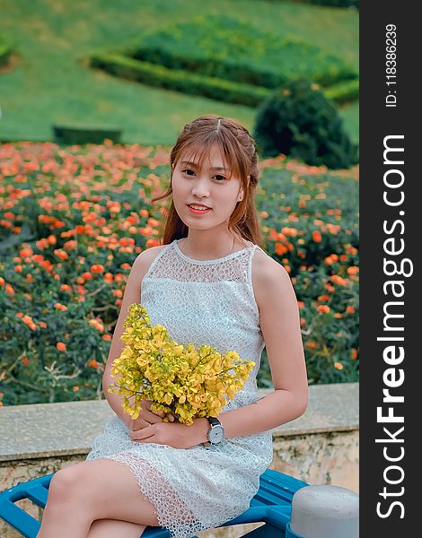 Focus Photo of Woman Wearing Dress While Holding Bouquet of Yellow Flowers