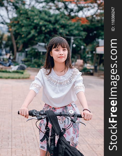 Woman Wearing White Blouse and Multicolored Floral Skirt Riding Bike