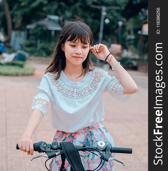 Woman Wearing White Blouse and Multicolored Floral Skirt Riding Bike