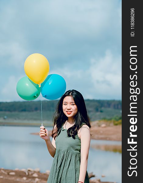 Woman Wearing Green Dress Holding Balloons Near River