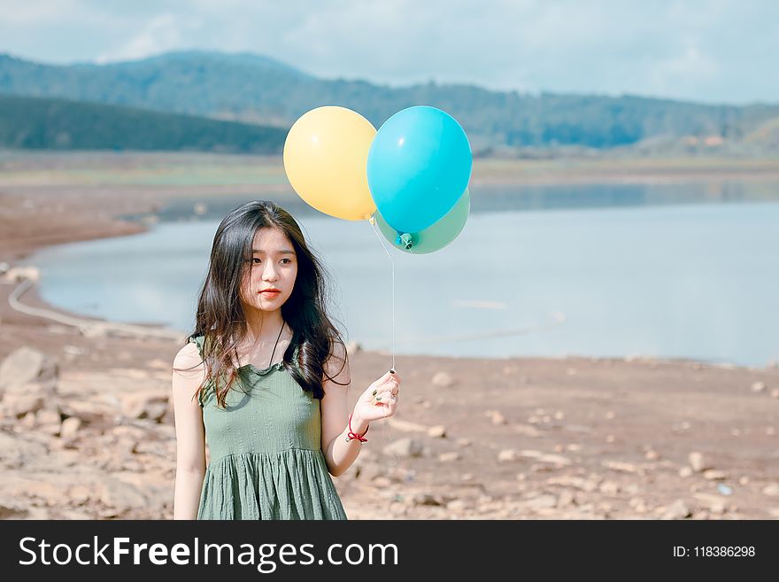 Shallow Focus Photography of Woman Holding Three Assorted-color Balloons