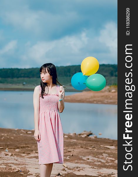 Woman Wearing Pink Dress Holding Three Balloons Near Body Of Water