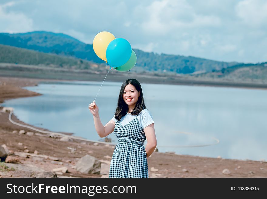 Woman Near Seashore Holding Balloons