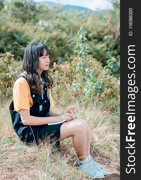 Photo Of Woman Sitting On Ground Surrounded By Grass, Trees, And Plants