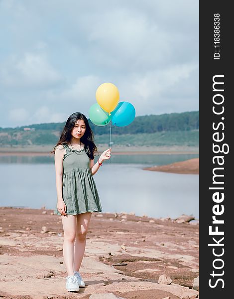 Woman&x27;s In Green Sleeveless Dress Holding 3 Balloons