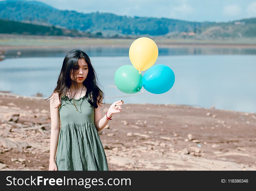Woman in Green Sleeveless Dress Holding Three Balloons