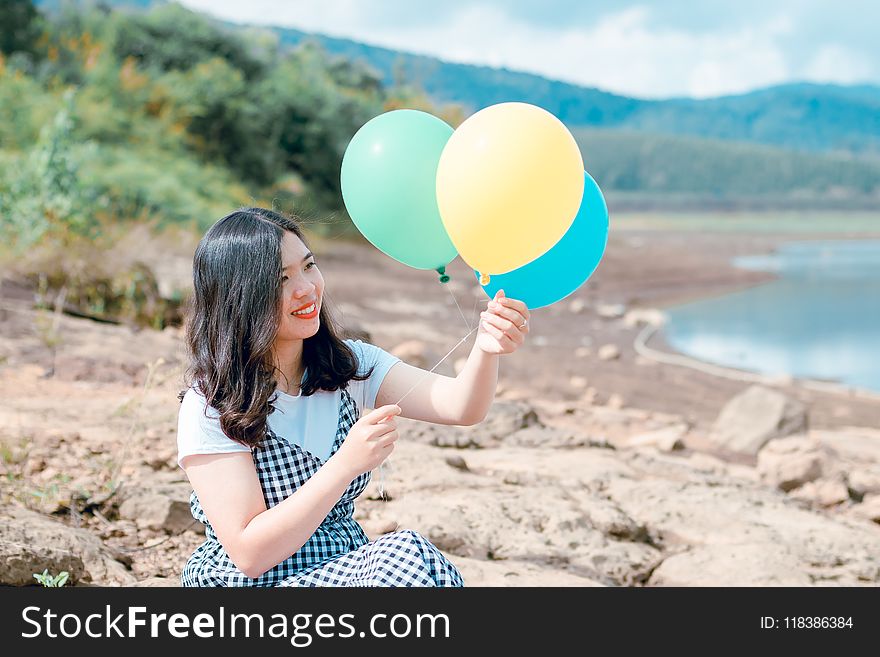 Woman in White and Black Dress Holding Three Balloons