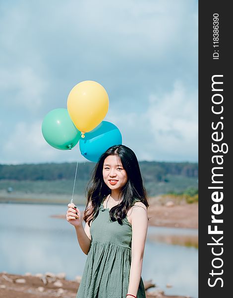 Woman in Green Sleeveless Top Holding Balloons