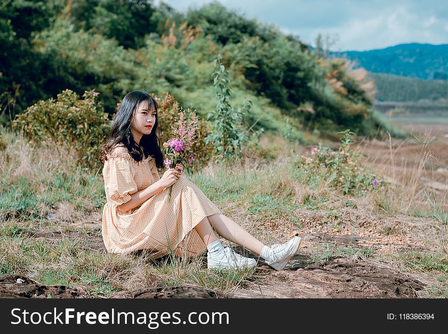 Woman With Beige Dress and White Shoes Sitting on Green Grass