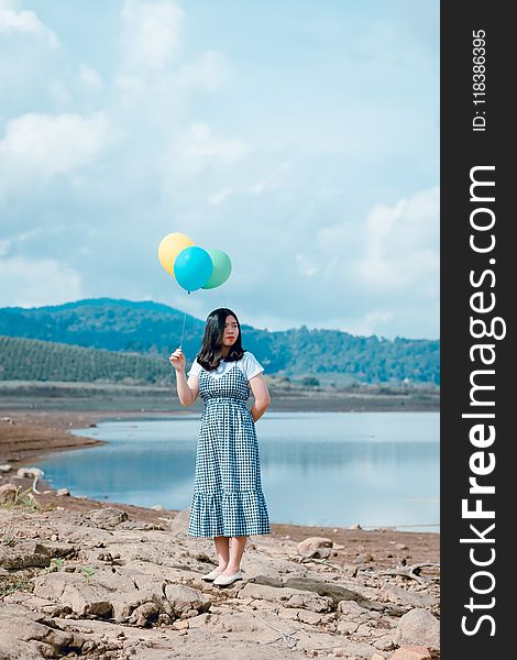 Woman Holding Balloons Near River