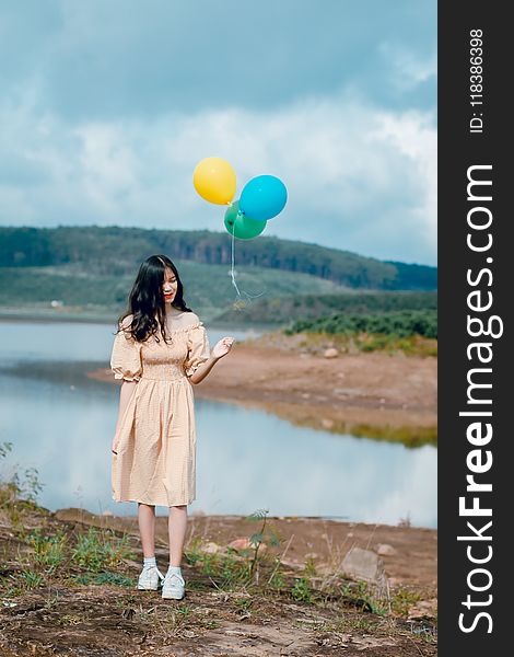 Woman in Beige Off-shoulder Dress Holding Balloons
