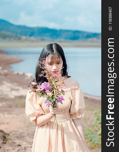 Woman in Orange and White Gingham Check Off-shoulder Dress Holding Pink Petaled Flowers