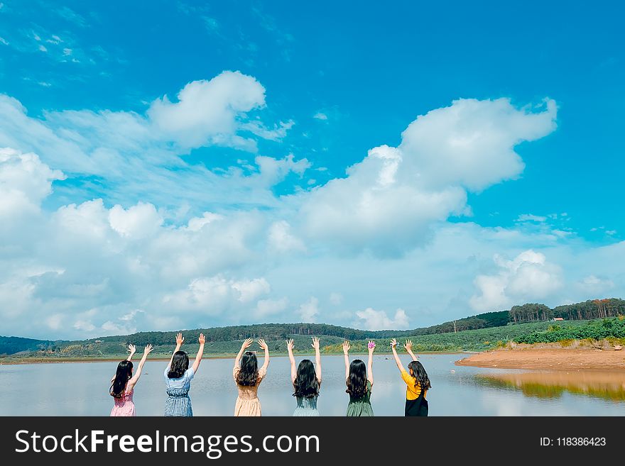 Group of Women Wearing Dress Raising Up Their Hands on Air Under Cloudy Sky