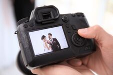 Professional Photographer Holding Camera With Lovely Wedding Couple On Display Royalty Free Stock Image