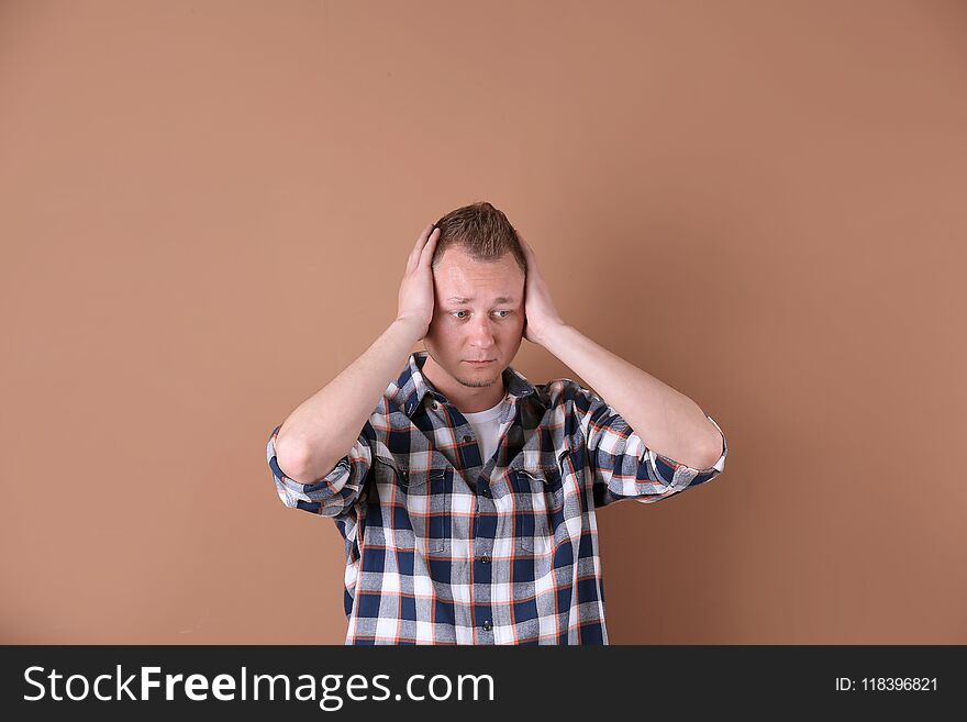 Handsome man suffering from headache on color background