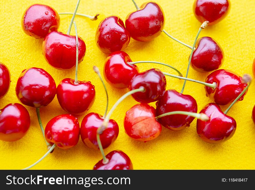 Closeup of red delicious cherries on a yellow background. Closeup of red delicious cherries on a yellow background