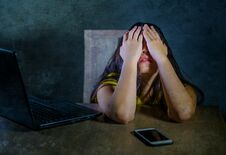 Young Latin Sad And Scared Woman Covering Face With Hands Desperate And Depressed With Laptop And Mobile Phone In Cyber Bullying P Stock Image