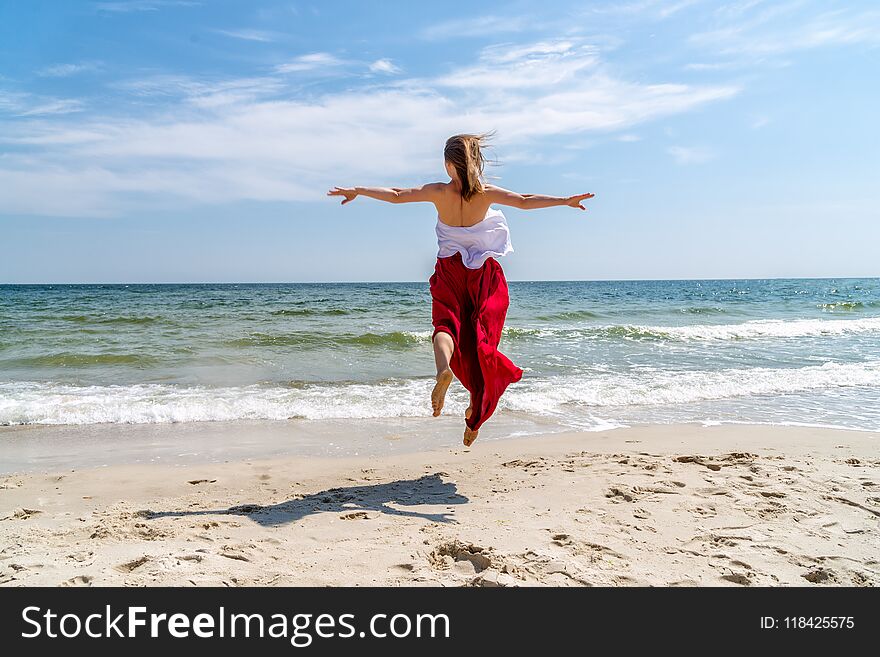 Beautiful girl in red dress by the sea.