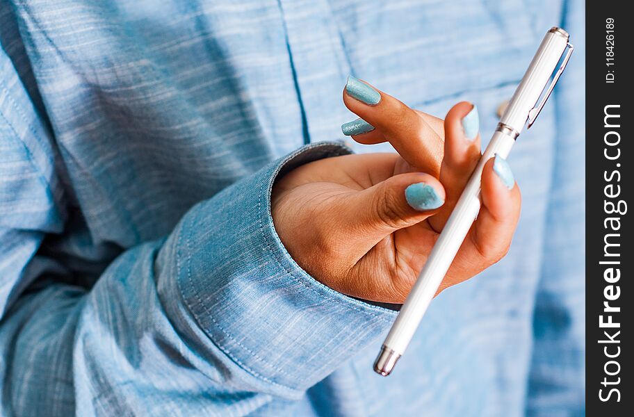 Cropped image of woman in blue shirt Hold pen in your hand. pen spinning