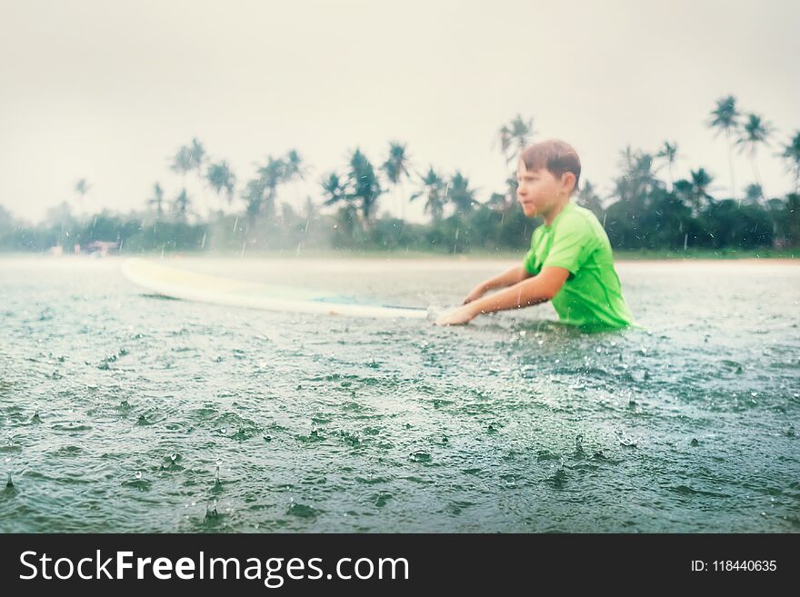 Boy first step surfer learning to surf under the rain