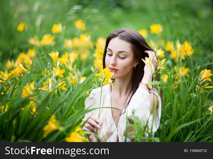 Attractive woman in yellow flowers day-lily field. Outdoor