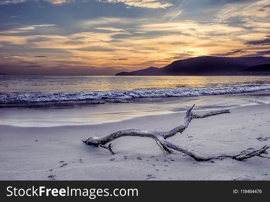 Body of Water Near Mountain Under Gray Sky at Golden Hour