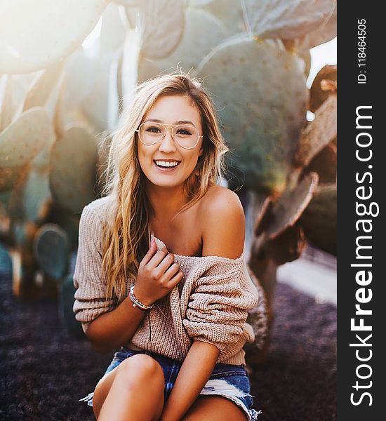 Woman In Brown Sweater And Distressed Blue Denim Shorts Beside Green Cactus
