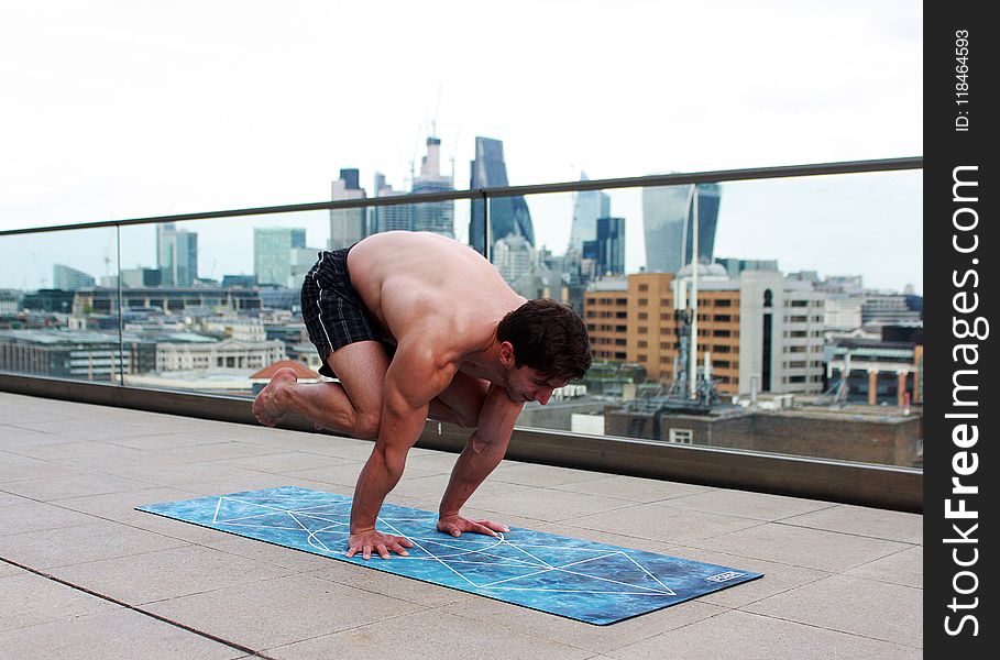 Man Doing Yoga on Mat Near Glass Balcony Fence