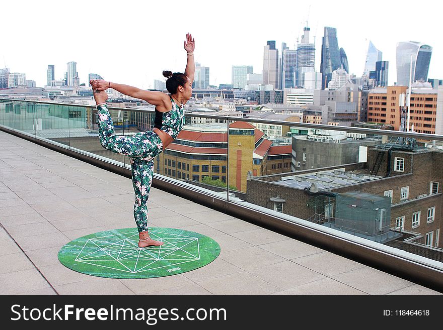 Woman on Round Green Yoga Mat Position in Right Leg High and Left Hand Upright Posiiton