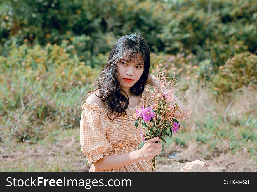 Shallow Focus Photography of Woman in Beige Off-shoulder Dress Holding Bouquet of Flowers