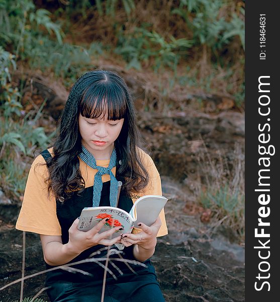 Woman In Orange And Black Top Holding White Book