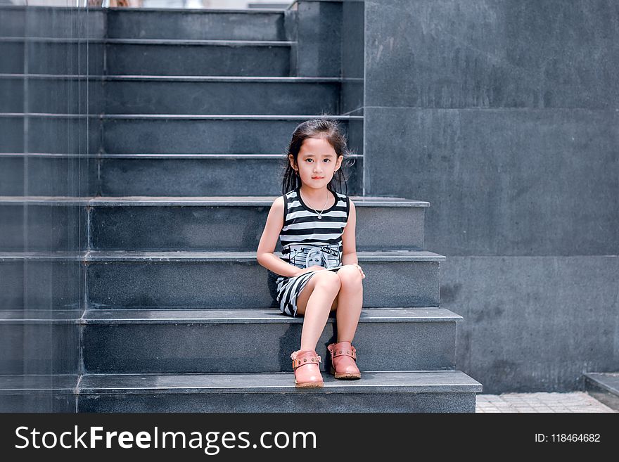 Girl Wearing Black and White Striped Dress Sitting on Stair